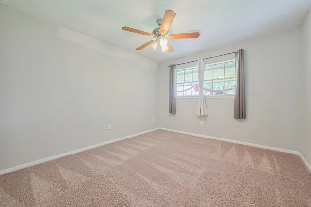 an empty room with window and ceiling fan