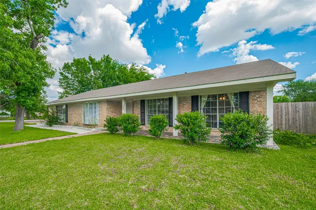 a front view of a house with a yard and large trees