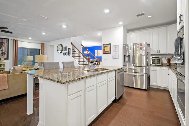 a kitchen with stainless steel appliances granite countertop a sink and a refrigerator