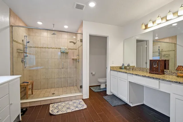 a bathroom with a granite countertop sink a toilet a mirror and shower