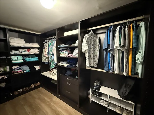 a view of walk in closet with clothes and shoes
