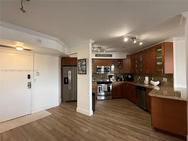 a kitchen with stainless steel appliances kitchen island granite countertop a refrigerator a sink dishwasher a stove with wooden cabinets and floor