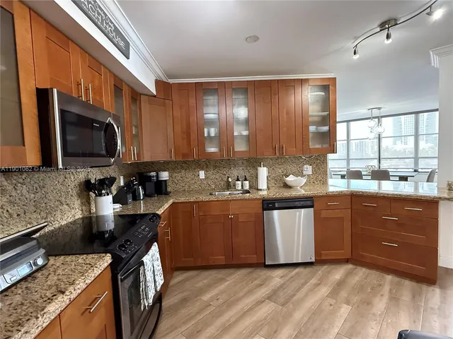 a kitchen with stainless steel appliances granite countertop a stove a sink dishwasher and a microwave oven with cabinets