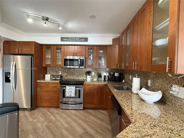 a kitchen with a refrigerator a stove top oven a sink dishwasher and wooden cabinets
