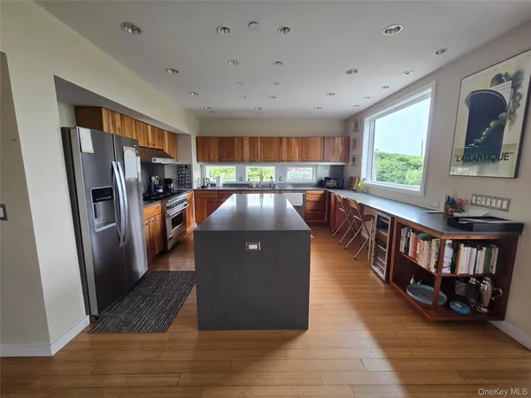 a kitchen with stainless steel appliances granite countertop a refrigerator a sink dishwasher a stove and a center island with wooden floor