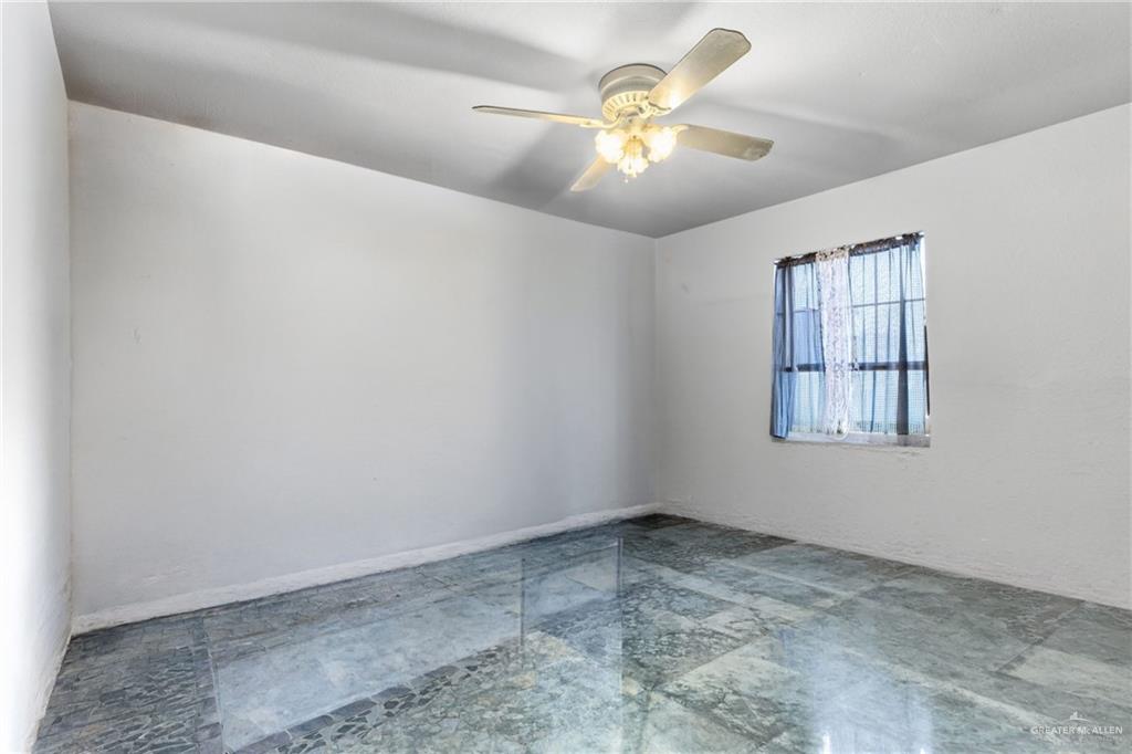 29246 26th Road San Benito, TX 78586 - Photo 7 of 23 Recessed window with security bars, ceiling fan with integrated lighting, and polished stone tile flooring