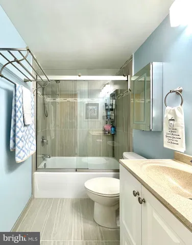 a bathroom with a granite countertop bathtub shower sink mirror and toilet