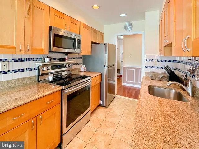 a kitchen with stainless steel appliances granite countertop a sink and a refrigerator