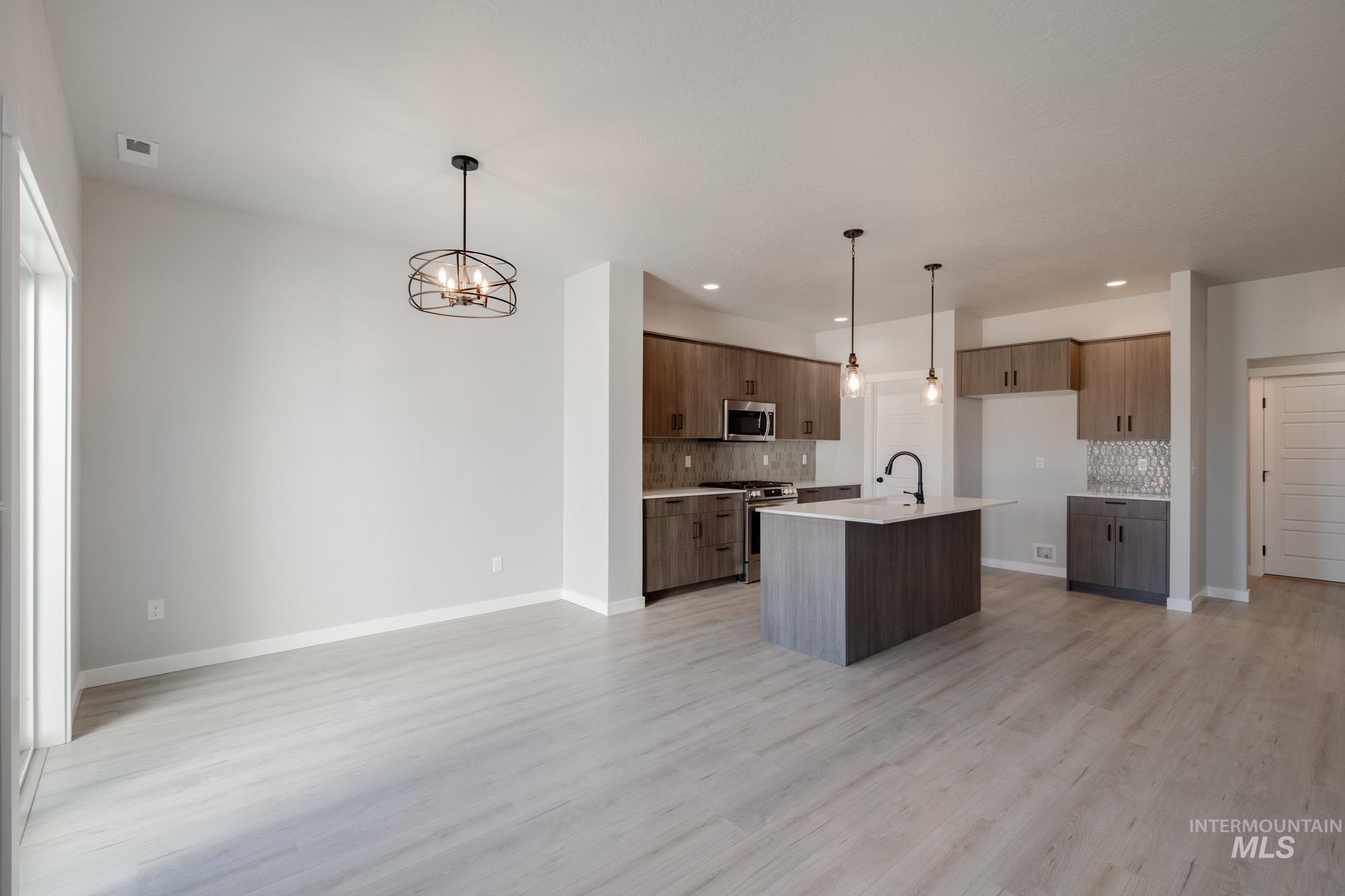 2168 South Border Way Meridian, ID 83642 - Photo 25 of 25 Kitchen with a kitchen island with sink, stainless steel appliances, suspended lighting, open floor plan, and light wood-style floors