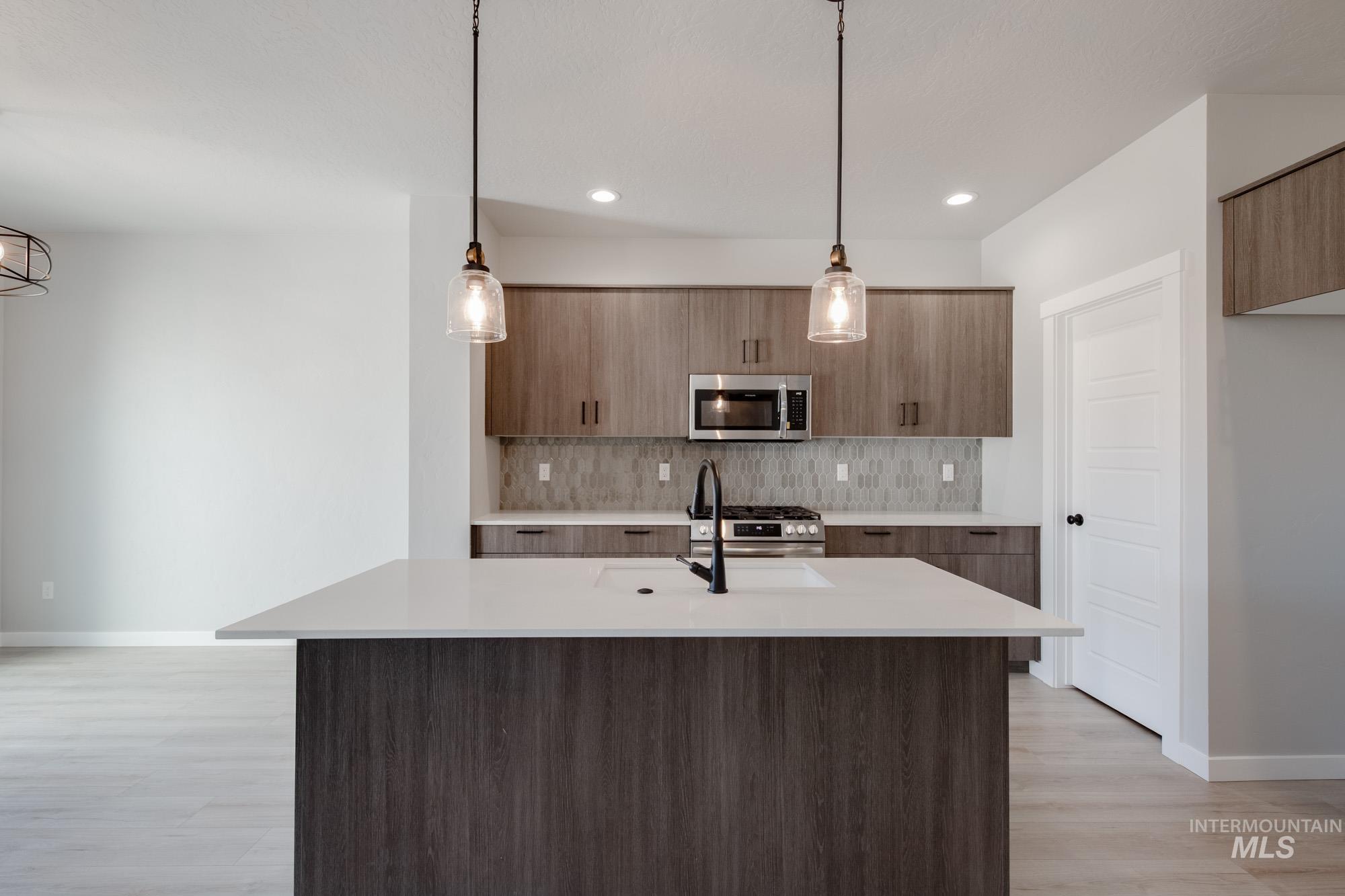 2168 South Border Way Meridian, ID 83642 - Photo 2 of 25 Kitchen featuring pendant lighting, modern cabinets, light stone counters, stainless steel appliances, and a kitchen island with sink