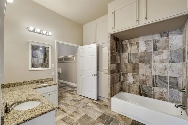 a bathroom with a granite countertop sink a toilet a shower and bathtub