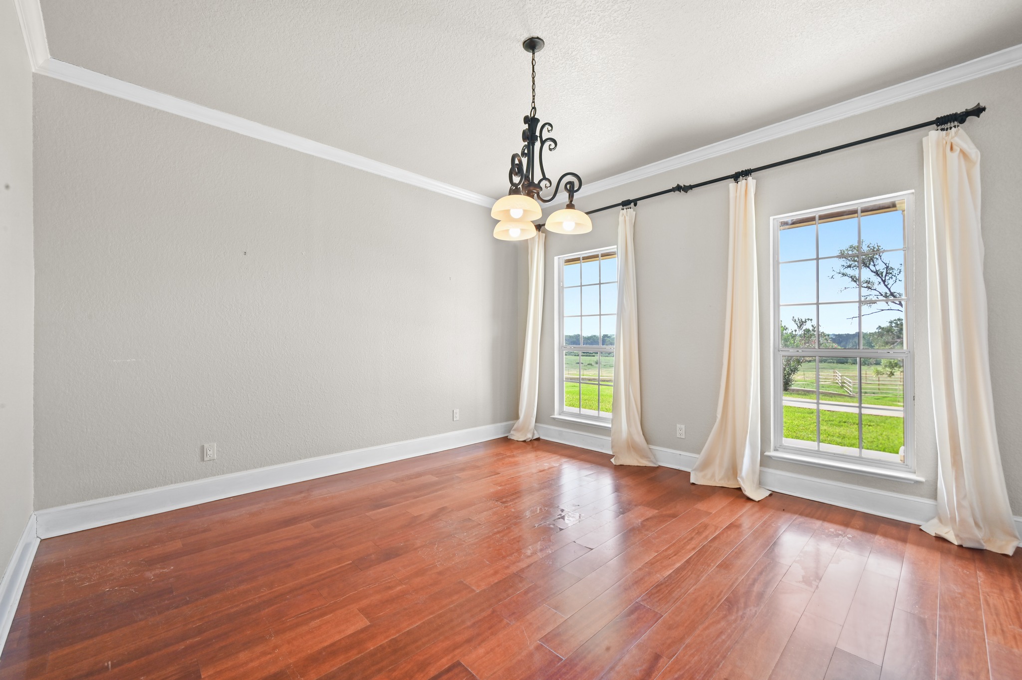 1175 Southern Way Luling, TX 78648 - Photo 16 of 40 Hardwood flooring extends throughout this naturally illuminated room, complemented by a classic chandelier.