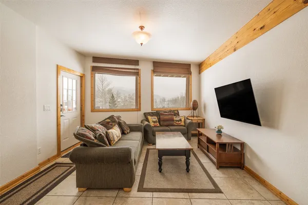 a living room with furniture a flat screen tv and a floor to ceiling window