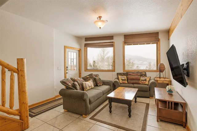 a living room with furniture a flat screen tv and a floor to ceiling window