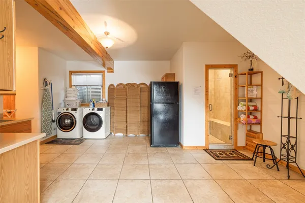 a utility room with stainless steel appliances a sink cabinets and a window
