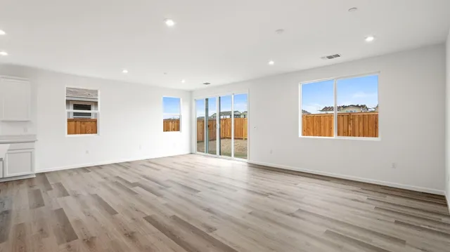 a view of an empty room with wooden floor and windows
