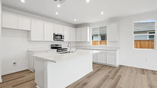 a kitchen with granite countertop white cabinets and black stainless steel appliances