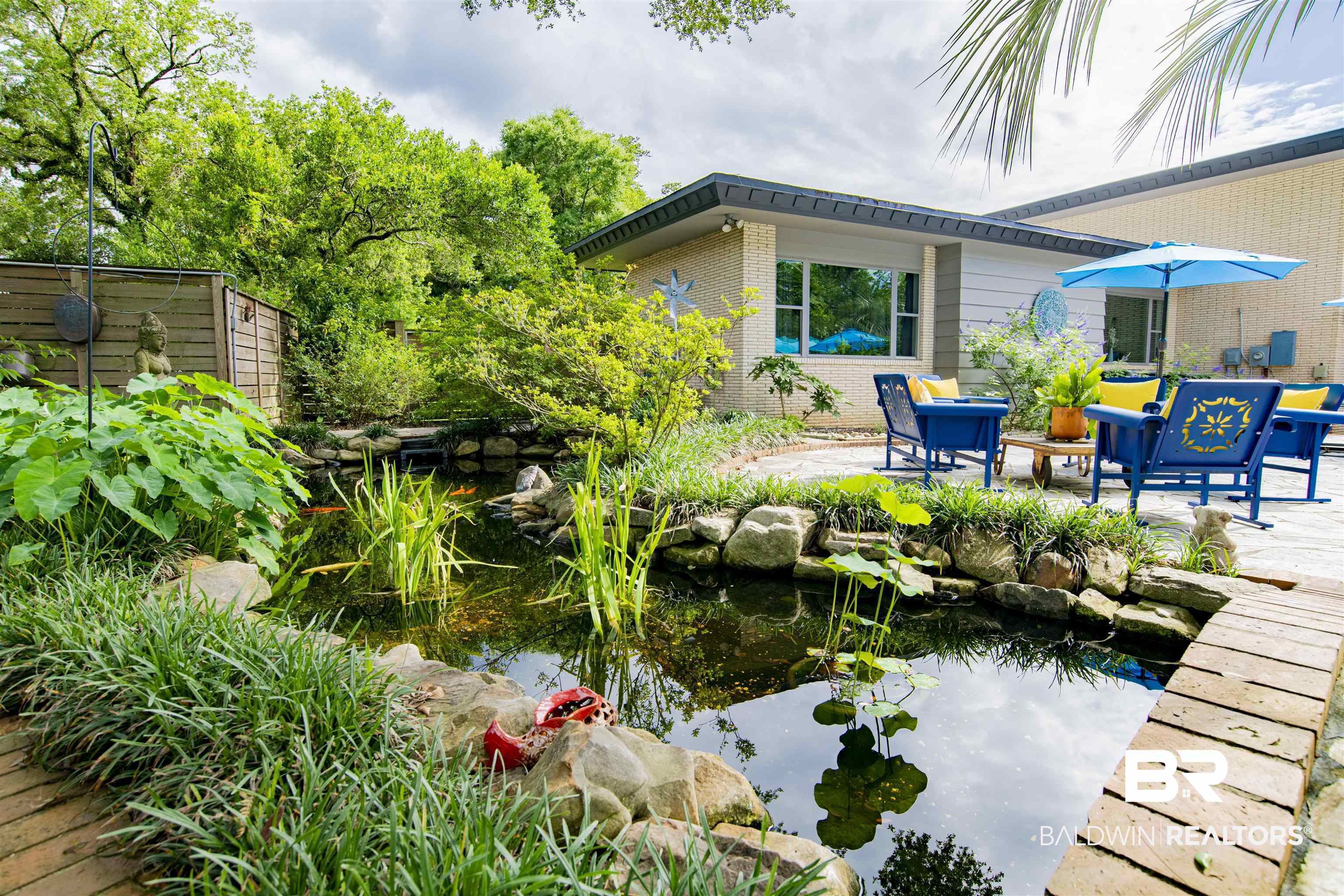 809 Bernard Circle Mobile, AL 36693 - Photo 70 of 75 Lush outdoor oasis featuring a stone-edged pond with aquatic plants, surrounded by vibrant greenery and mature trees