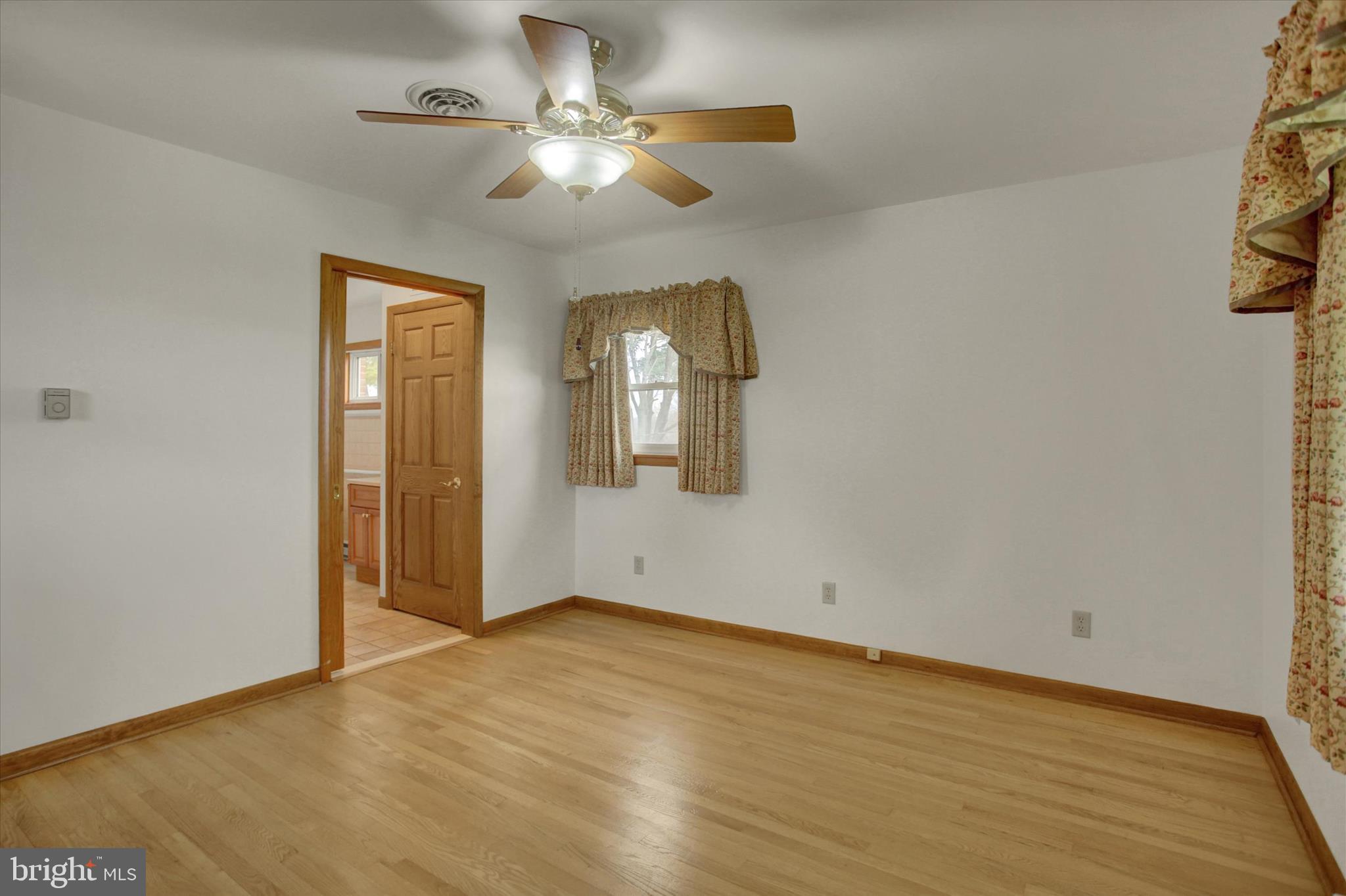 18514 Indian Cottage Road Hagerstown, MD 21742 - Photo 9 of 56 an empty room with wooden floor chandelier fan and windows