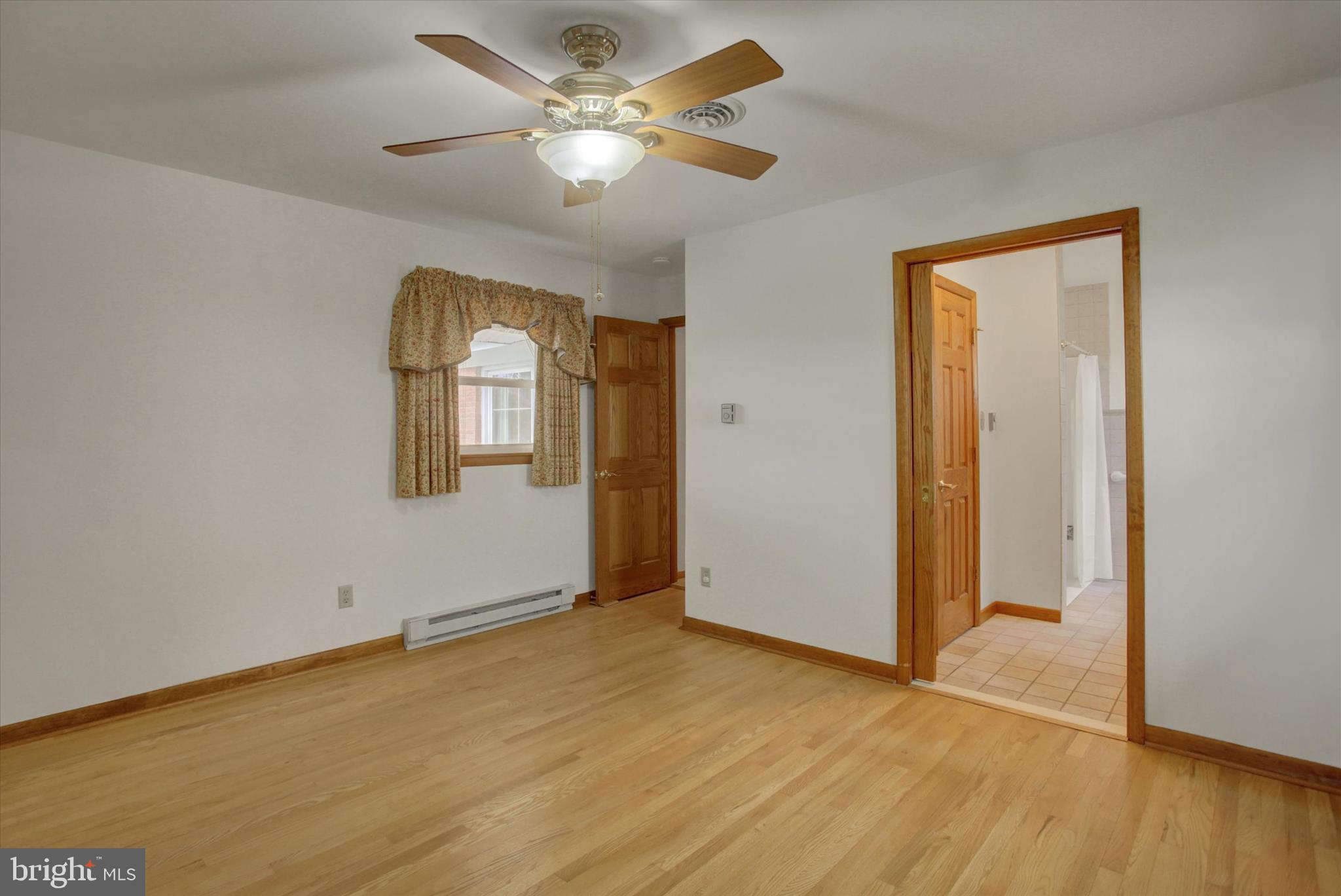 18514 Indian Cottage Road Hagerstown, MD 21742 - Photo 10 of 56 an empty room with wooden floor chandelier fan and windows