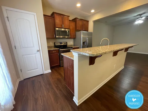 a kitchen with kitchen island a sink wooden floor and stainless steel appliances