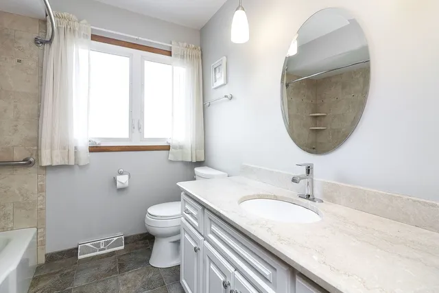 a bathroom with a granite countertop sink a toilet and a mirror