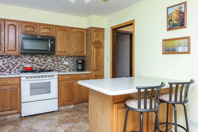 a kitchen with stainless steel appliances granite countertop a stove a microwave a sink and white cabinets