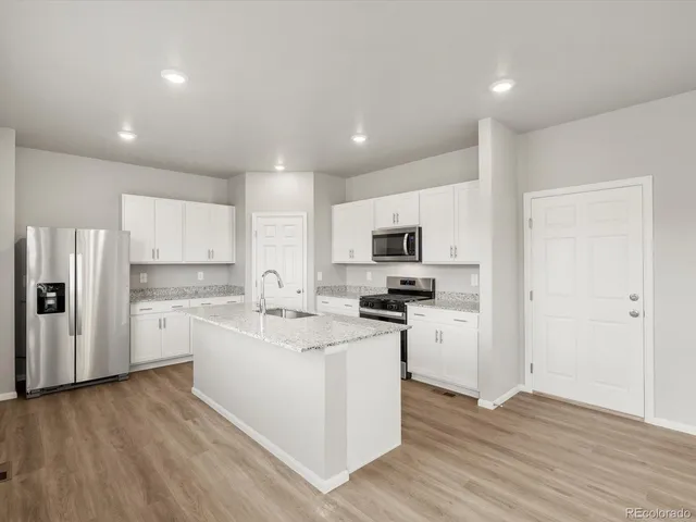 a kitchen with appliances a sink a refrigerator and cabinets