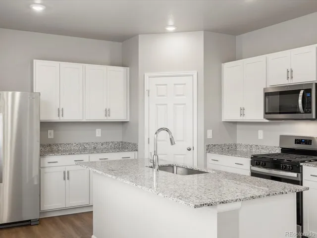 a kitchen with granite countertop a sink a stove and cabinets