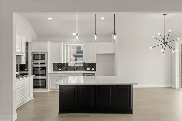 a large white kitchen with a sink and dishwasher a stove with wooden floor