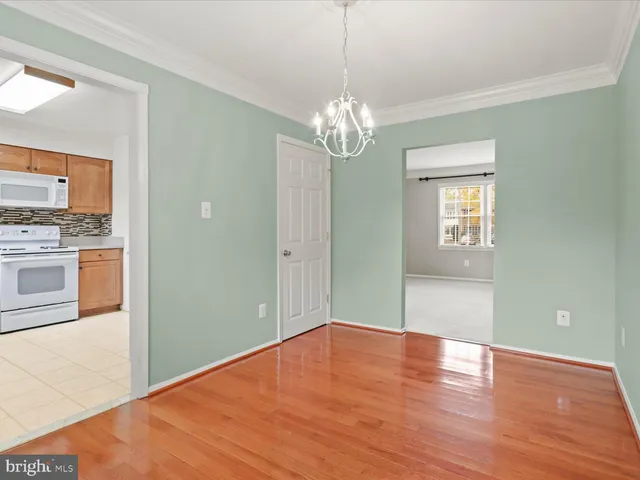 a view of empty room with wooden floor and kitchen view