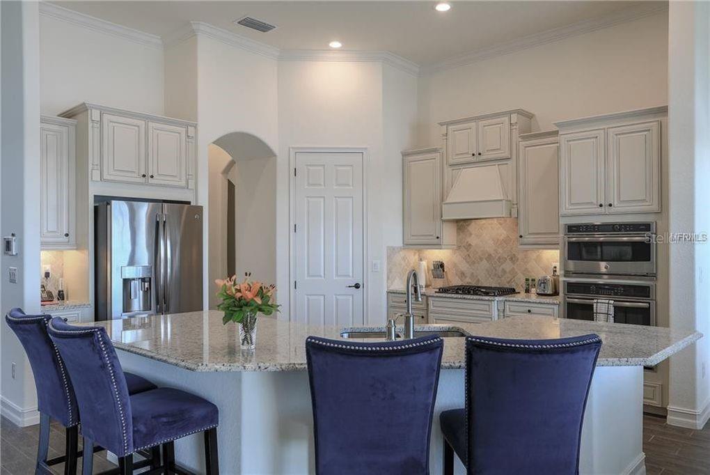 5528 Arnie Loop Lakewood Ranch, FL 34211 - Photo 7 of 59 a kitchen with stainless steel appliances granite countertop a dining table chairs stove refrigerator and cabinets