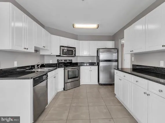 a kitchen with granite countertop a sink a stove top oven and refrigerator
