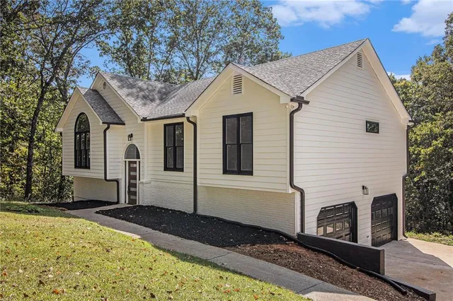a view of a white house with a large window and potted plants