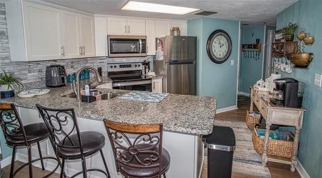 a kitchen with stainless steel appliances granite countertop a table chairs a stove and a refrigerator