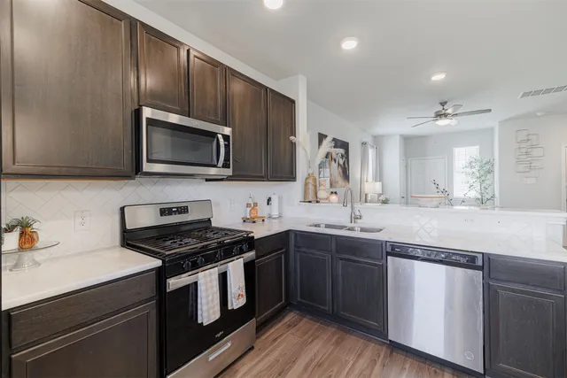 a kitchen with granite countertop stainless steel appliances a sink cabinets and wooden floor