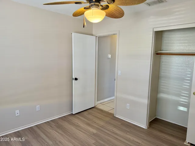 an empty room with wooden floor closet and windows
