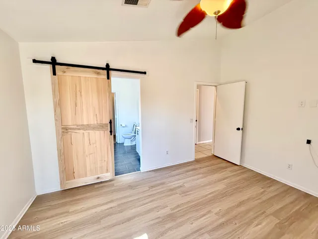 an empty room with wooden floor and a ceiling fan