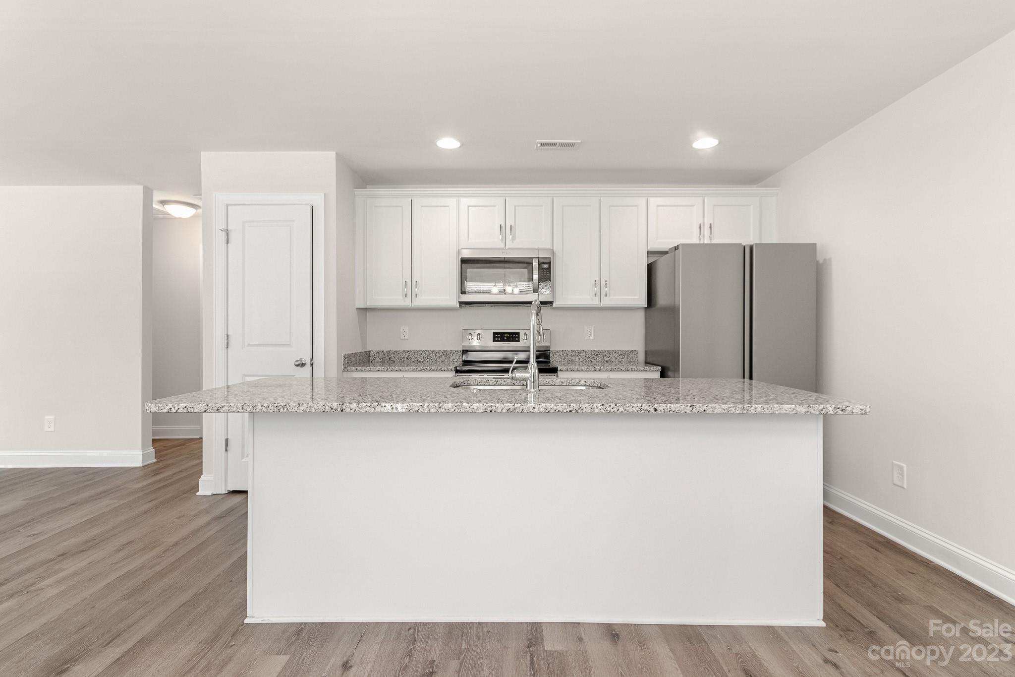 318 Springhill Lane Maiden, NC 28650 - Photo 11 of 40 a kitchen with stainless steel appliances granite countertop a refrigerator a stove a sink and white cabinets with wooden floor