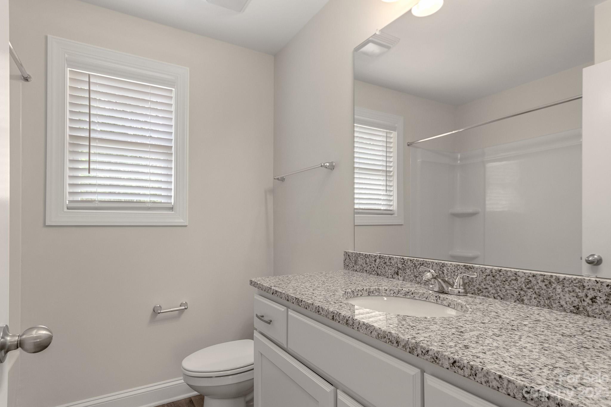 318 Springhill Lane Maiden, NC 28650 - Photo 31 of 40 a bathroom with a granite countertop sink toilet a mirror and a window