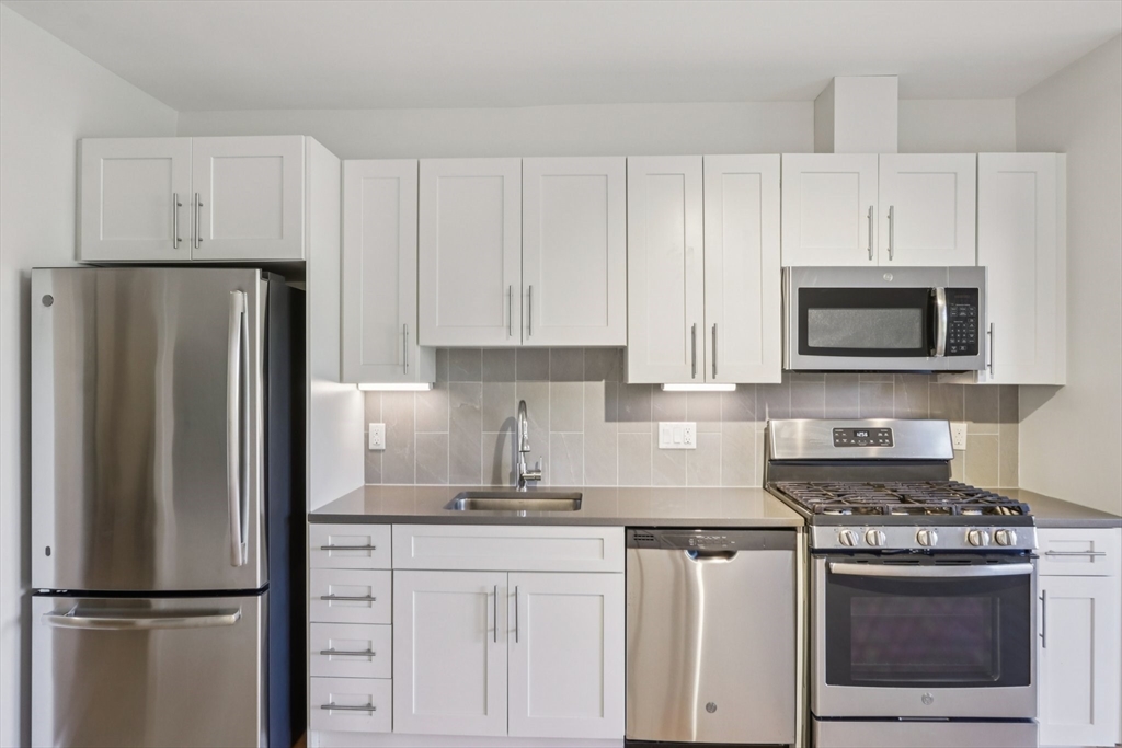 a kitchen with white cabinets and stainless steel appliances