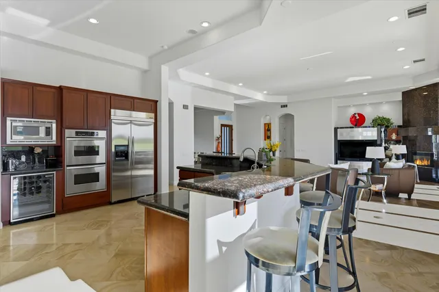 a kitchen with stainless steel appliances kitchen island granite countertop a table and chairs in it