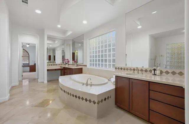 a spacious bathroom with a tub a double vanity sink a mirror and a shower