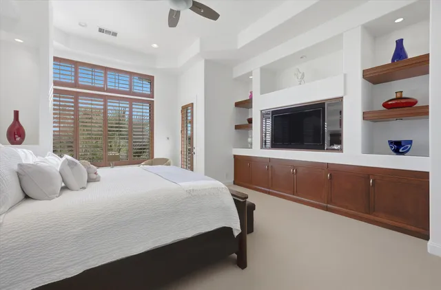 a bedroom with a large bed and a flat tv screen on dresser