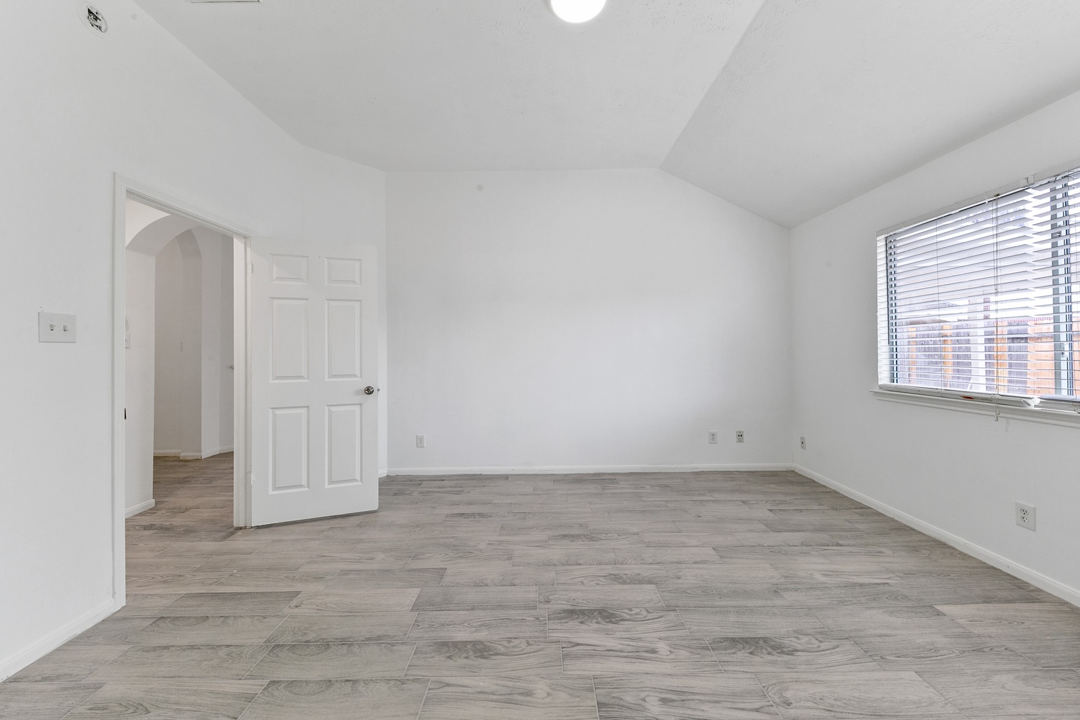12014 Raven View Drive Houston, TX 77067 - Photo 21 of 29 This room features a bright, spacious layout with light wood flooring and neutral walls. It has a large window for natural light and an open entryway with a white door. Perfect for a bedroom or office space.