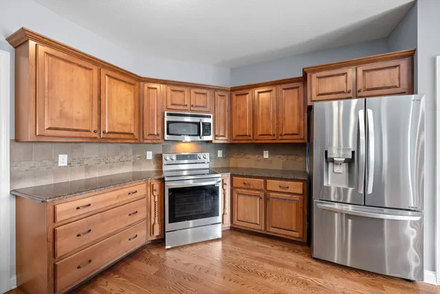 a kitchen with granite countertop wooden cabinets stainless steel appliances and a window