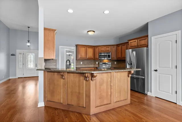 a kitchen with stainless steel appliances a refrigerator and wooden floor