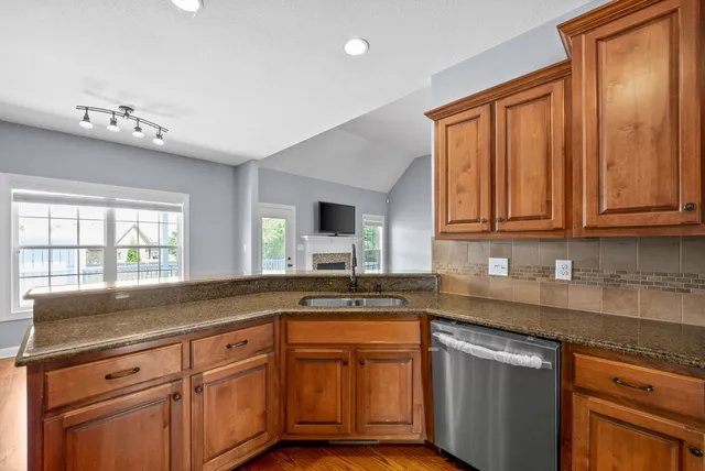 a kitchen with granite countertop stainless steel appliances a sink window and cabinets