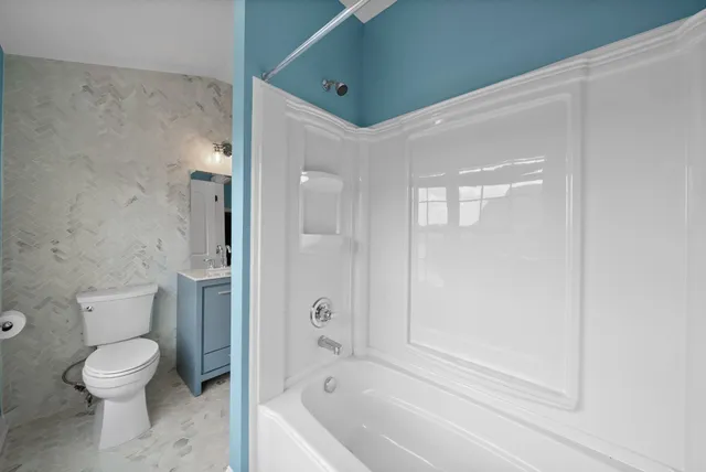a bathroom with a granite countertop sink a toilet and a window