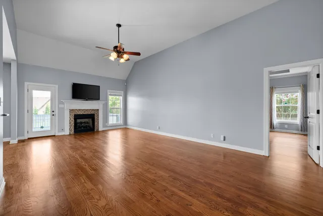 an empty room with wooden floor fireplace and windows